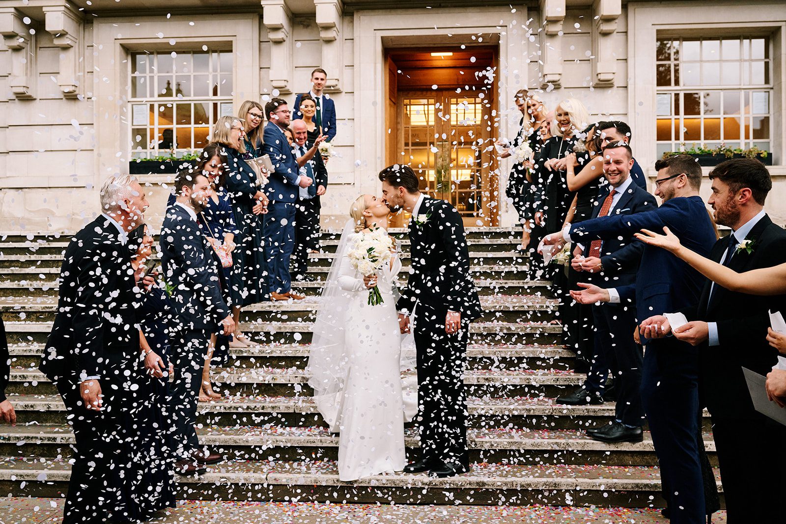 Wedding guests throwing confetti over the couple on the steps of Hackney Town Hall